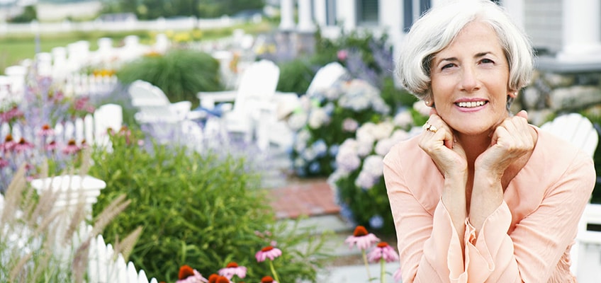 A woman sitting outside in a full bloom garden.