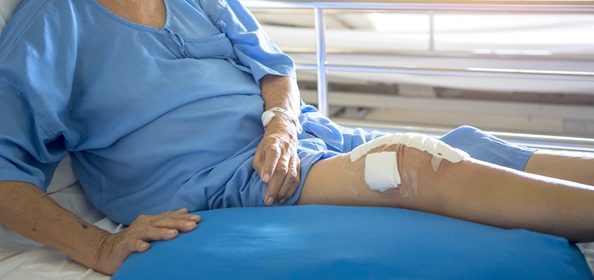 A patient in a hospital bed with dressings on his wounds.