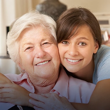 A grandmother and granddaughter smiling together.