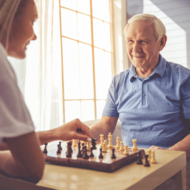 A senior playing chess with another person.