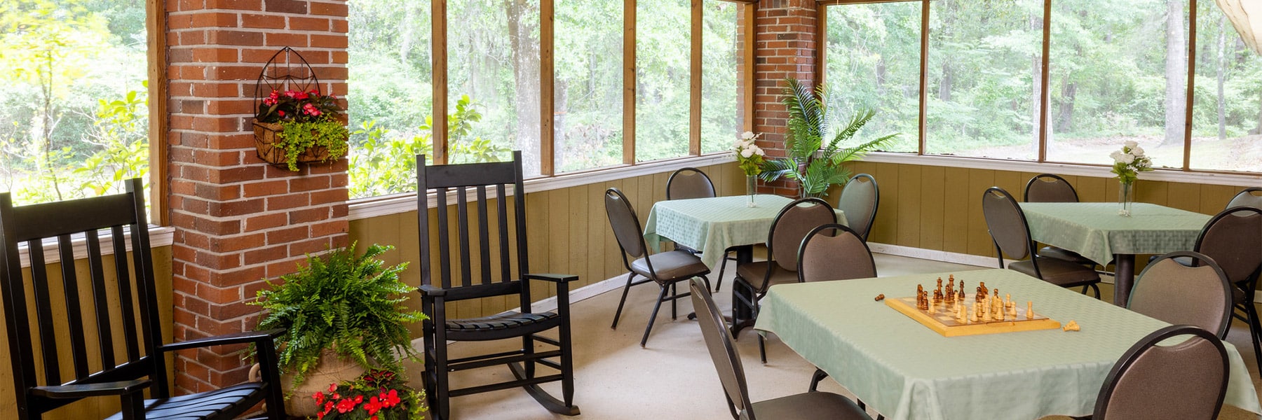 Screened in porch with tables at Johns Island Post Acute