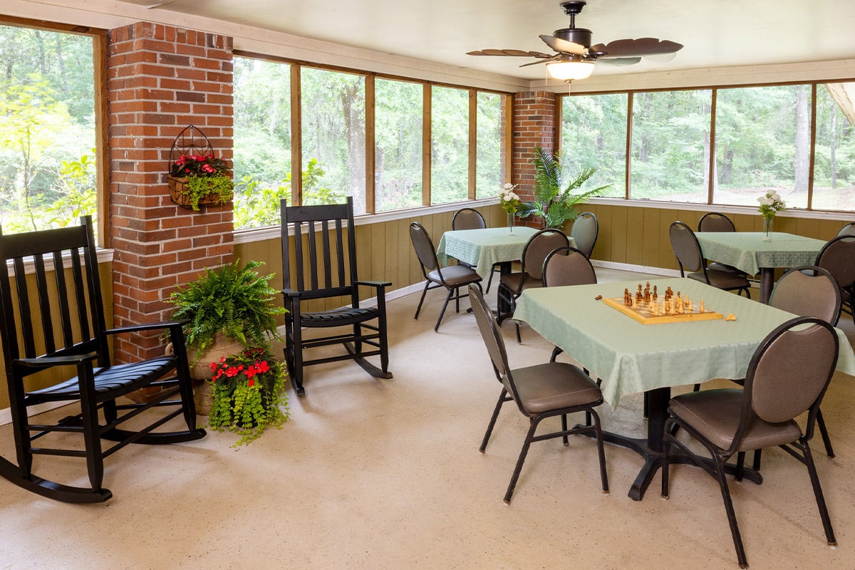 Screened in porch with tables at Johns Island Post Acute