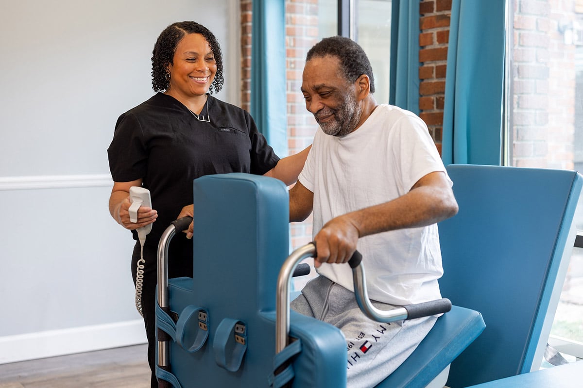 Physical therapist helping patient on machine at Johns Island Post Acute